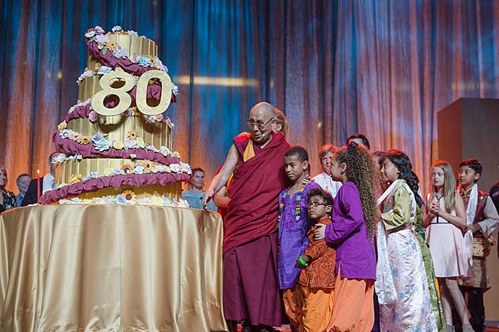 在美國80歲生日慶典現場，達賴喇嘛站在四層高的特製生日蛋糕旁。