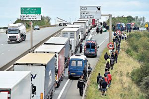 French riot police stand on the side of the road to prevent migrants from approaching lorries on the road leading to the ferry port in Calais, northern France, on August 5,2015. Britain and France were to announce a new "command and control centre" on August 20 for tackling smuggling gangs in Calais, where thousands of migrants desperate to cross the Channel are living in slum-like conditions. AFP PHOTO / PHILIPPE HUGUEN